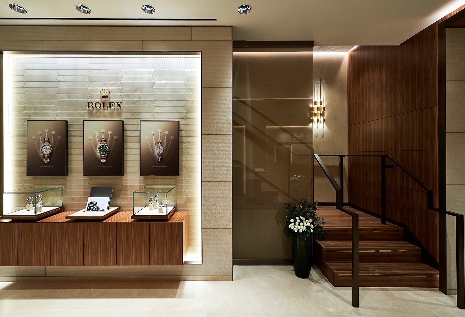 Rolex display wall beside a stair within a restrained timber and stone interior