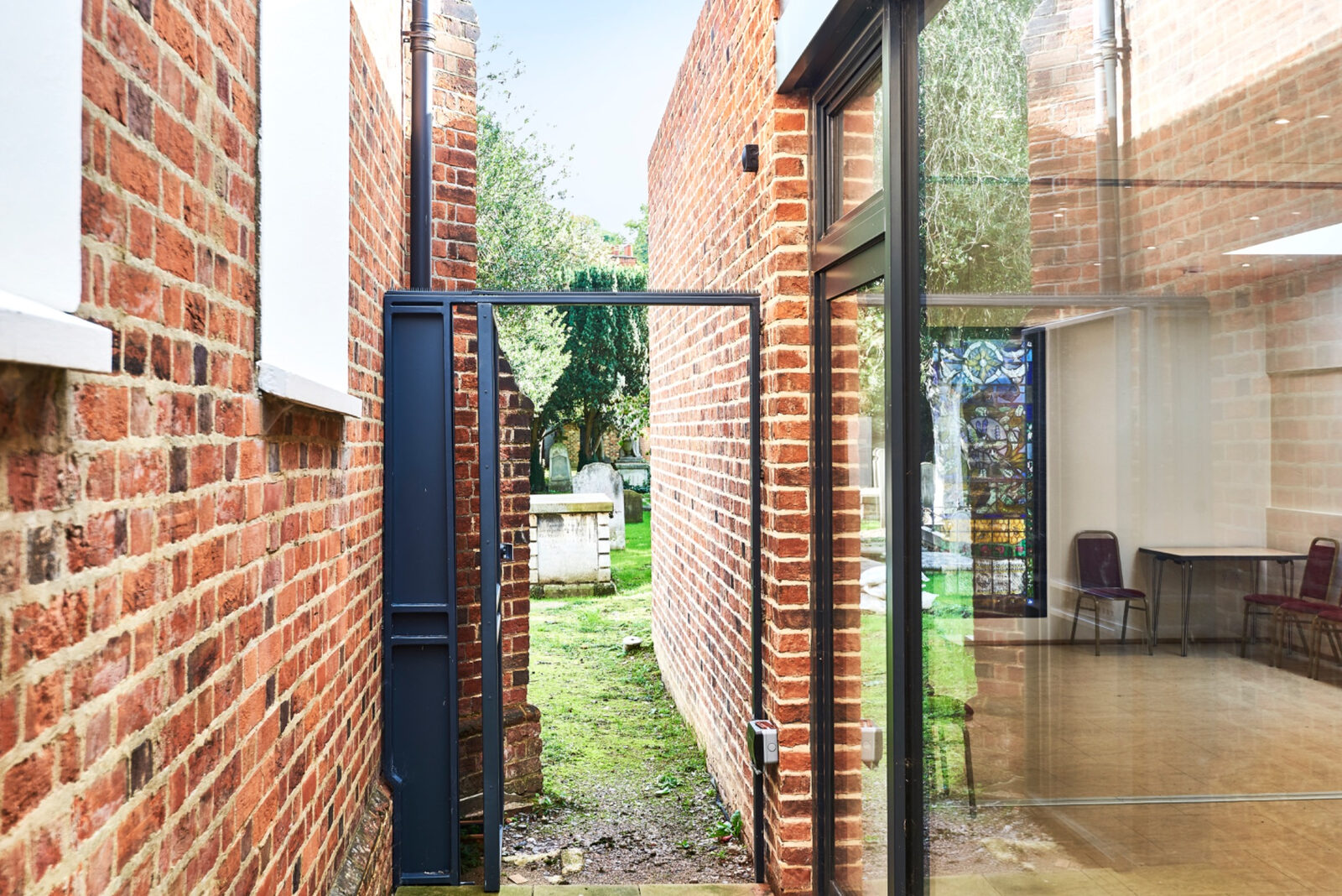 Glazed threshold between brick walls with the churchyard visible beyond