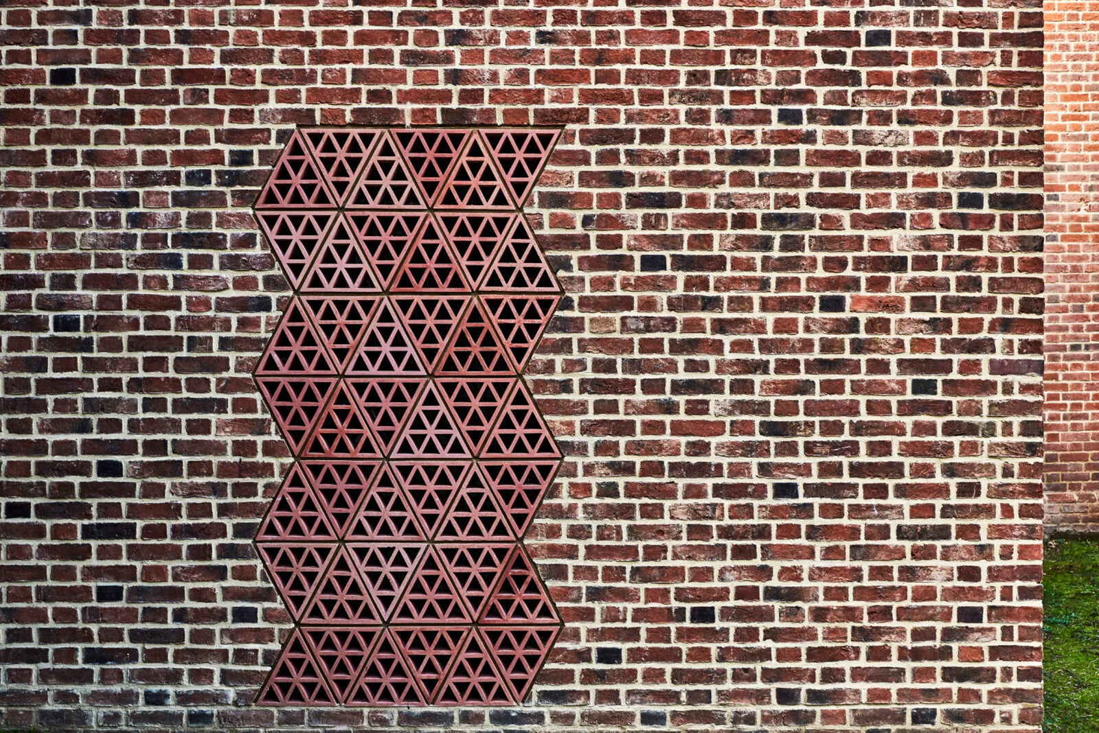 Geometric perforated metal screen set within the new brick wall